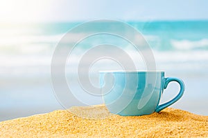 blue coffee cup on sand beach