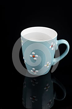 Blue coffee mug isolated above black background with reflections
