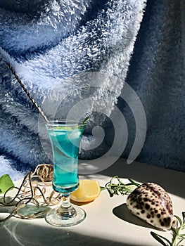 Blue cold drink in a glass with ice cubes on white desk