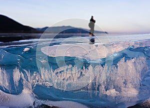 Blue and cold ice of Lake Baikal. Silhouette of a man