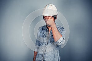 Blue collar worker covering his face
