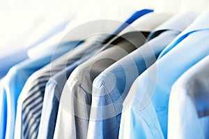 Blue color clothes. Male clothes, jackets and shirts hanging on clothes rail. Copy space. Banner