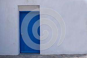 Blue color door on a white wall, greek island architecture, copy space