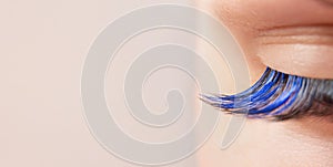 Blue color eyelash extensions. Trendy false lash style close-up, closed eye macro. Wide banner or background with copy space