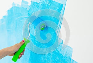 Blue color painting wall with roller in hand.