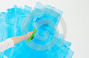 Blue color painting wall with roller in hand.