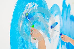 Blue color painting wall with roller in hand.