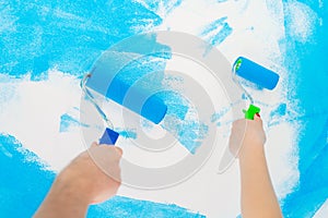 Blue color painting wall with roller in hand.