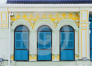 Blue color wooden arched window on green and yellow cement wall in chino Portuguese style at Phuket old town, Thailand