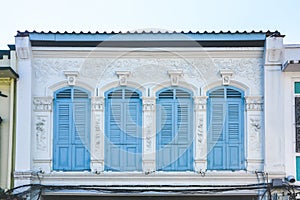 Blue color wooden arched window on white cement wall in chino Portuguese style at Phuket old town, Thailand