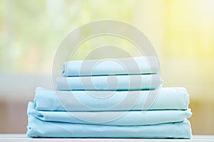 Blue colored bedding on a blurred background. Stack of folded new sheets on the table