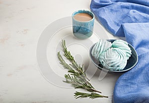 Blue colored homemade zephyr or marshmallow with cup of coffee on white wooden background. side view, copy space