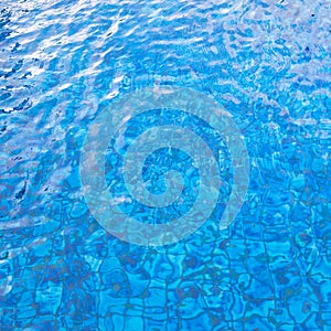 Blue colored pool pattern with bright and dark parts and sun reflections