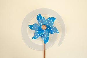 Blue colored wind mill toy on beige background, abstract textured backdrop
