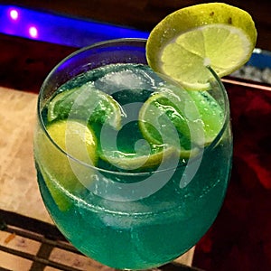 A blue coloured sparkling mocktail with lemon