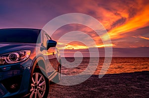 Blue compact SUV car with sport and modern design parked by beach at sunset. Hybrid and electric car technology. Car parking space