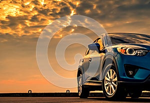 Blue compact SUV car with sport and modern design parked on concrete road by the sea with beautiful sunset sky.  Hybrid