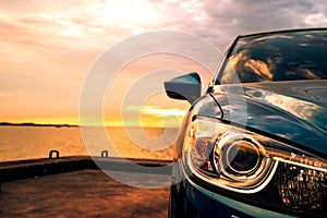 Blue compact SUV car with sport and modern design parked on concrete road by the sea at sunset. Environmentally friendly