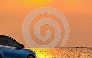 Blue compact SUV car with sport and modern design parked on concrete road by the sea at sunset. Environmentally friendly