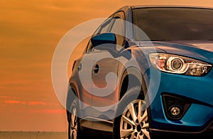 Blue compact SUV car with sport and modern design parked on concrete road by the sea at sunset in the evening. Hybrid and electric