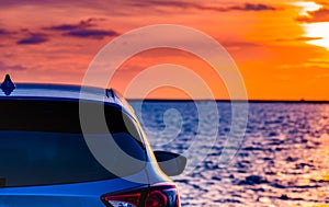 Blue compact SUV car with sport and modern design parked on concrete road by the sea at sunset.Hybrid auto and automotive.