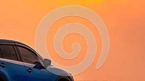 Blue compact SUV car with sport and modern design parked by the sea with beautiful orange sunset sky. Road trip travel. Electric