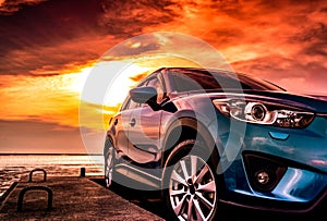 Blue compact SUV car with sport, modern, and luxury design parked on concrete road by the sea at sunset. Front view of beautiful photo