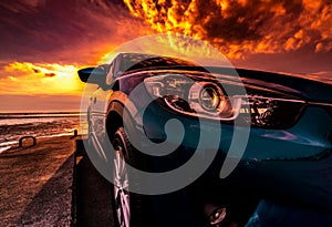 Blue compact SUV car with sport, modern, and luxury design parked on concrete road by the sea at sunset. Front view of beautiful h