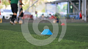 Blue cone marker and soccer ball moving on green artificial turf