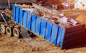 Blue construction debris container filled with rock and concrete rubble. Industrial garbage bin