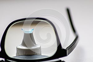 Blue contact lens through black eyeglasses shows different eyewear to correct farsightedness and nearsightedness by optometry