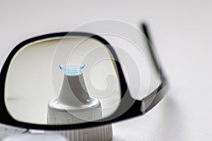 Blue contact lens through black eyeglasses shows different eyewear to correct farsightedness and nearsightedness by optometry