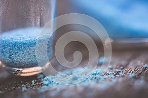 blue copper sulphate granules in glass floors on wooden table