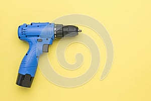 Blue cordless screwdriver on a yellow background