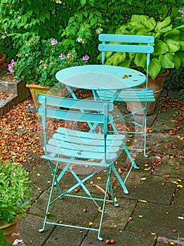 Blue courtyard metal chairs and table in serene, peaceful, lush, private backyard at home on a summers day. Patio