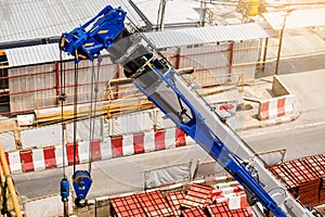 Blue crane boom with hooks and sling cable at construction site
