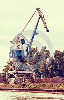 Blue crane in cargo port, retro photo filter