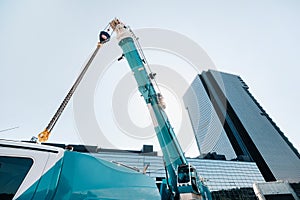 Blue crane lifting mechanism with hooks near the glass modern building, crane and hydraulic high lift up to 120 meters