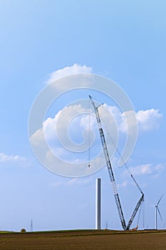 Blue crane tower constructing windmill with background of blue sky. Wind Turbine Construction