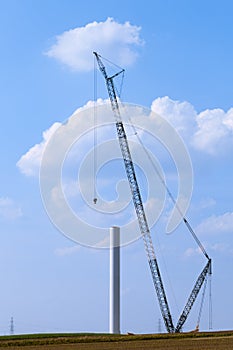 Blue crane tower constructing windmill with background of blue sky. Wind Turbine Construction