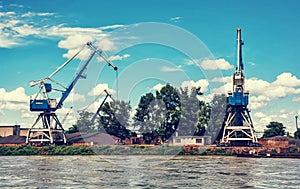 Blue cranes in cargo port, Danube river, retro photo filter