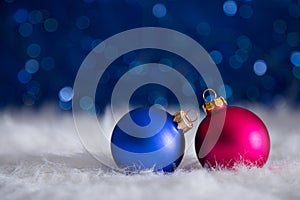 Blue and crimson Christmas balls on white fur with garland light