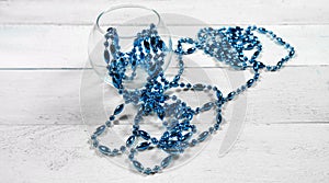 Blue cristal beads and transparent vase on white wooden background. minimalistic home decor concept