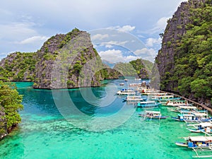 Blue crystal water in paradise Bay with boats on the wooden pier at Kayangan Lake in Coron island, Palawan, Philippines