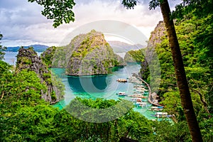 Blue crystal water in paradise Bay with boats on the wooden pier at Kayangan Lake in Coron island, Palawan, Philippines