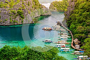 Blue crystal water in paradise Bay with boats on the wooden pier at Kayangan Lake in Coron island, Palawan, Philippines