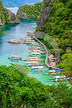 Blue crystal water in paradise Bay with boats on the wooden pier at Kayangan Lake in Coron island, Palawan, Philippines