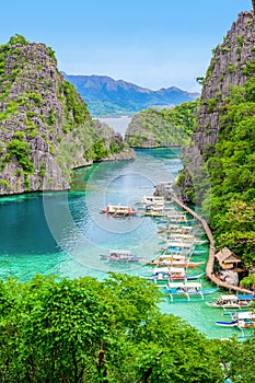 Blue crystal water in paradise Bay with boats on the wooden pier at Kayangan Lake in Coron island, Palawan, Philippines