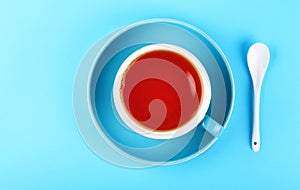 Blue cup of black red tea over blue background