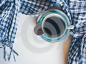 Blue cup of coffee, chocolate cookie and a checkered scarf on white